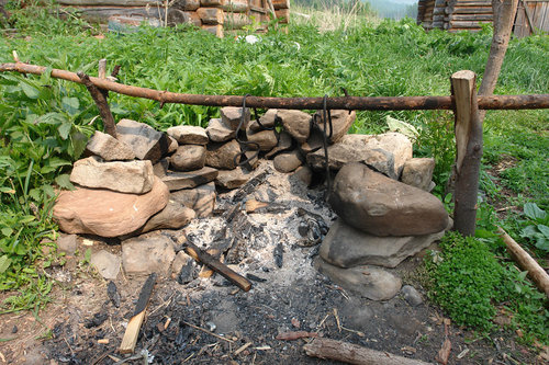 Уличный очаг защищен от ветра каменной стенкой.